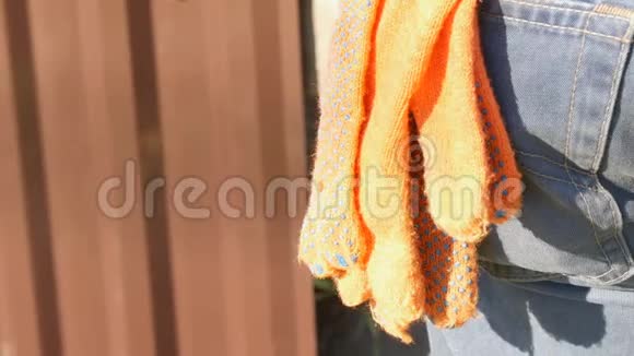 橙色建筑手套在工人牛仔裤后口袋的裤子里视频的预览图