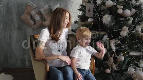 年轻的母亲在圣诞树上和儿子玩耍视频的预览图