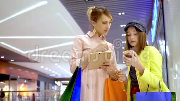 母亲和她的成年女儿使用平板电脑计划在商场购物视频的预览图