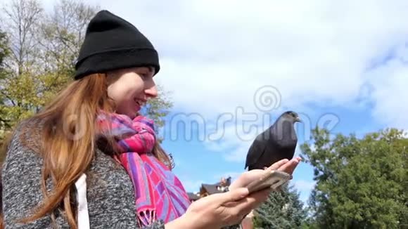 一个年轻的女人用她的手机在她的手上打一只鸽子视频的预览图