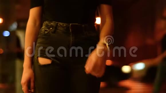 晚上穿着牛仔裤和t恤的女孩拿着一只钟在城里转悠视频的预览图