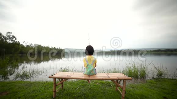 快乐的女孩拉着鱼竿在湖边钓鱼视频的预览图