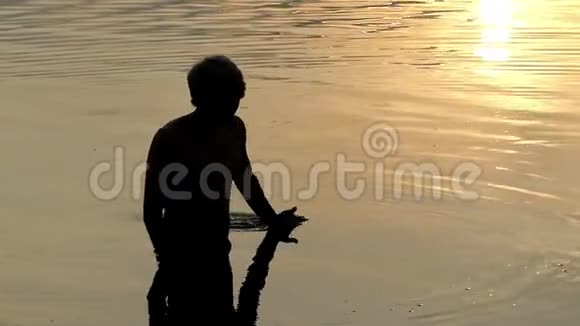 阿蒂人在河流中移动他的手看着日落视频的预览图