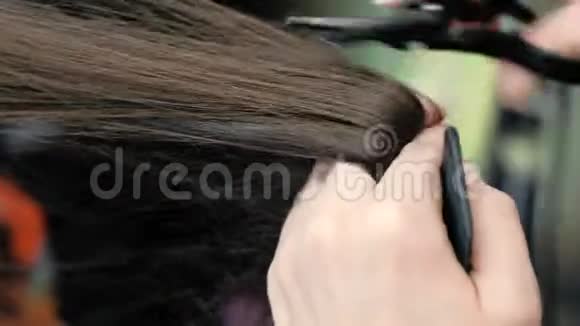 理发师他的手剪着长长的黑发头发热剪刀特写镜头视频的预览图