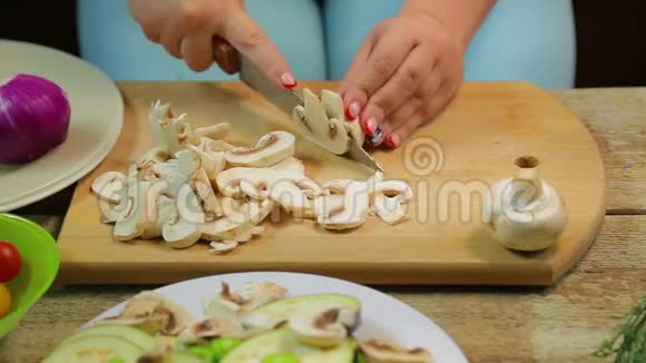 一个女人用一把刀在木板上把香瓜蘑菇切成薄片视频的预览图