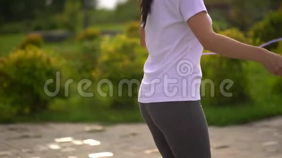 年轻女子在公园里跳绳把她的脚和屁股收起来慢动作视频的预览图