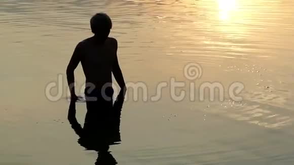 日落时分年轻人在水中绕着他旋转视频的预览图