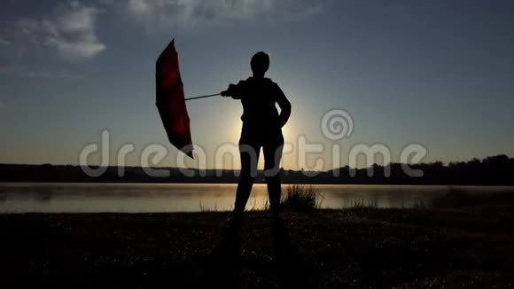 放松的女人在日落时用棕色的伞视频的预览图