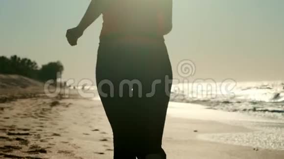 20岁的女孩在日落时在沙滩上奔跑在户外慢跑视频的预览图