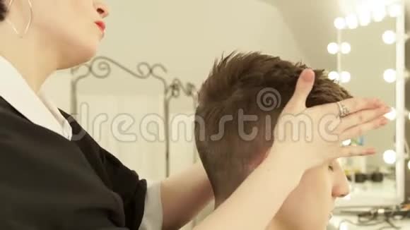 专业发型师在美发沙龙做男式发型理发师在理发后完成发型视频的预览图