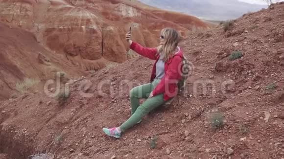 女孩游客在相机智能手机上自拍红色的山脉和红色的地球就像火星一样视频的预览图