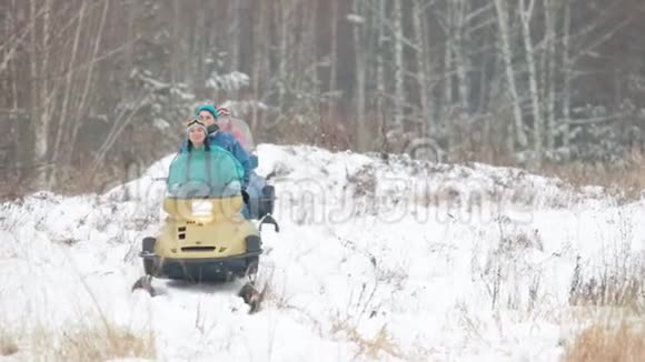 穿着五颜六色衣服的家庭在冬天的森林里骑着雪地摩托视频的预览图