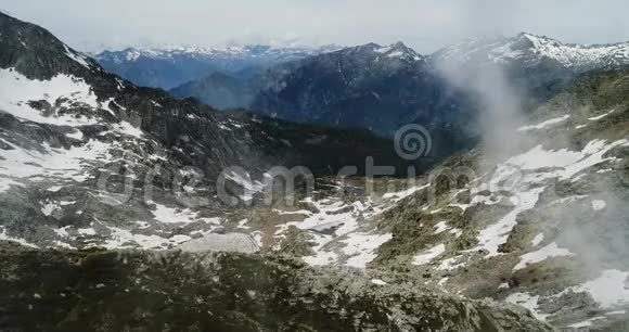 在晴朗的日子里在多云的多岩石雪山上的侧面鸟瞰意大利阿尔卑斯山脉夏季与视频的预览图