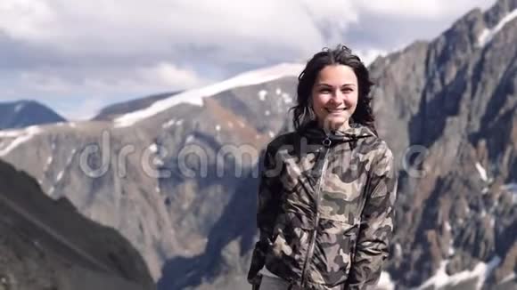 山背景上的年轻女子穿着夹克笑得很开心旅行者视频的预览图