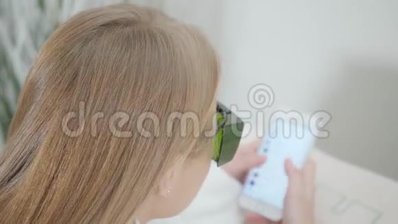 戴护目镜的女孩的肖像用电话激光脱毛和美容女士腿上的脱毛化妆品视频的预览图