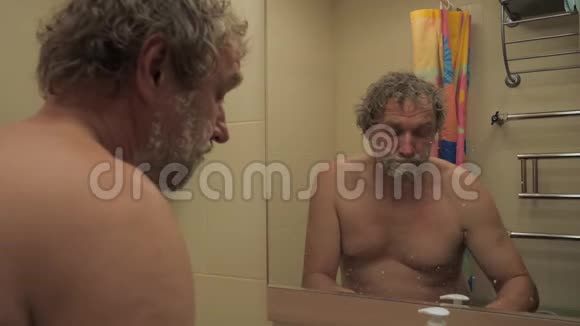 镜子前洗澡的人用剃刀剃胡须视频的预览图