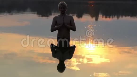 年轻人站在湖水中在灿烂的夕阳下翩翩起舞视频的预览图