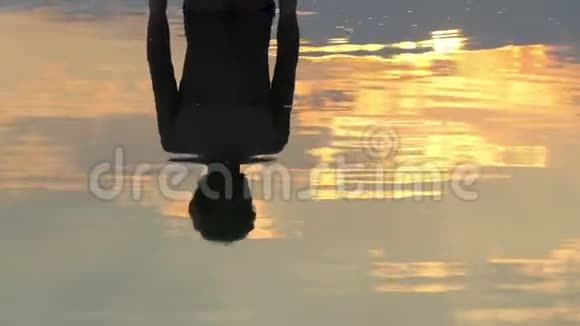 快乐的人站在韦茨湖在日落时展现一个拇指向上的姿态视频的预览图