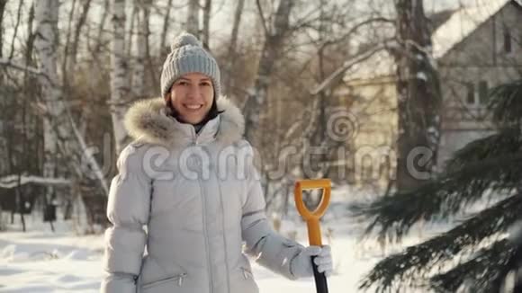 冬天在郊区快乐的年轻女子用铲子在镜头前摆姿势视频的预览图