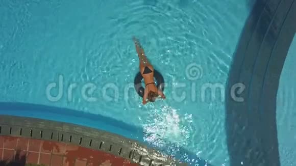 女孩躺在游泳池的救生圈里放松视频的预览图