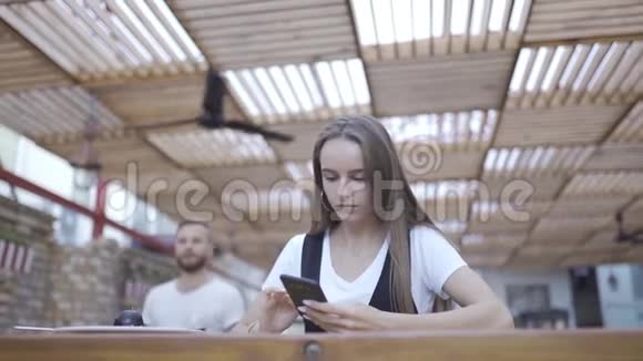 美丽的年轻女子在咖啡馆里使用现代智能手机在手机上输入短信视频的预览图