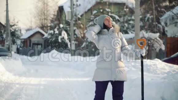 冬天在郊区快乐的年轻女子用铲子在镜头前摆姿势视频的预览图