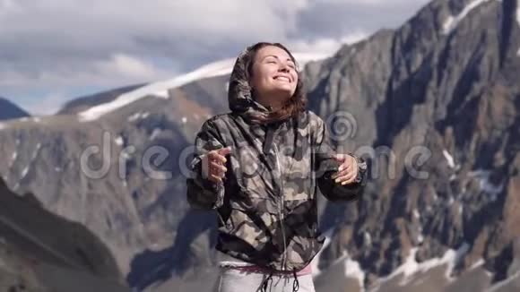 山背景上的年轻女子穿着夹克笑得很开心旅行者视频的预览图