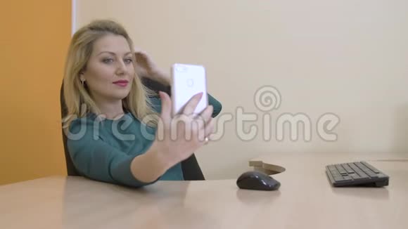 美丽的商务女性微笑着在手机上摆出自拍照片视频的预览图