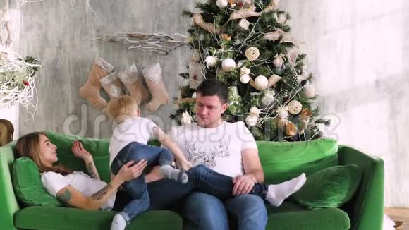 一家人聚集在圣诞树周围在沙发上玩圣诞节室内视频的预览图