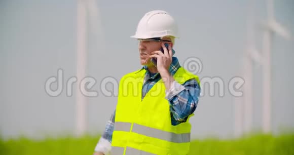 愤怒的工程师用手机对着风车农场说话视频的预览图