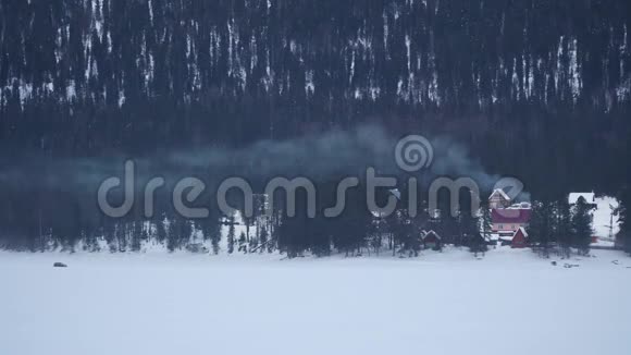 冬天森林里烟囱冒出烟的乡下房子视频的预览图