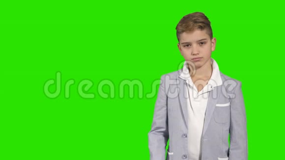 穿西装的小男孩用手指指着绿色背景的东西视频的预览图