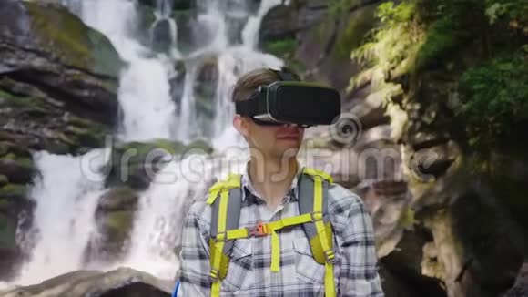一个戴着虚拟现实头盔的人在森林中的瀑布视频的预览图