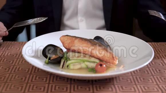 在精致的餐厅里用海鲜和蔬菜菜肴装饰盘子穿西装的人正在吃这道菜视频的预览图