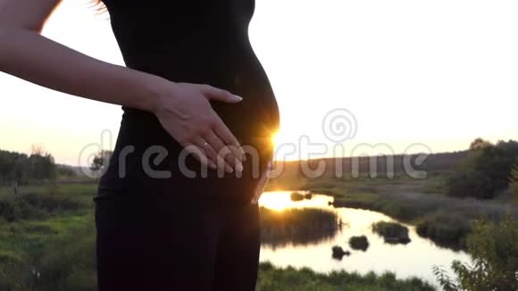 日落时年轻的孕妇抚摸着她未来的孩子视频的预览图