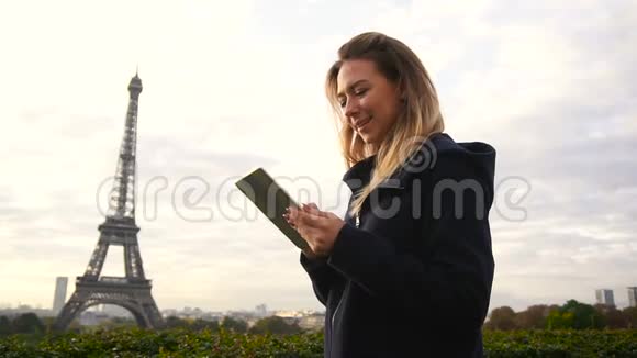 美丽的女人打字信息平板电脑与埃菲尔铁塔背景慢动作视频的预览图