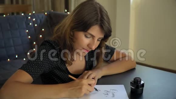 一位年轻女子用刻字技巧在纸上书写书法的特写镜头她写着梦想远大的目标视频的预览图