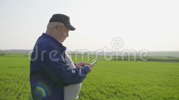 成熟的农民检查土壤和使用智能手机检查报告的农业领域视频的预览图