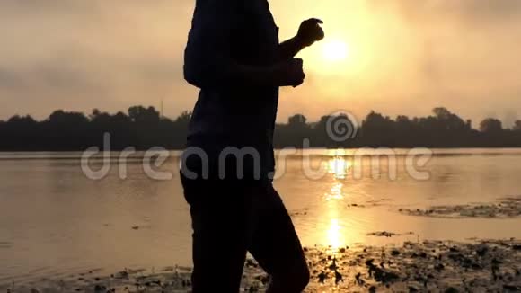 在斯隆莫的夕阳下幸福的男人在一个脆弱的河岸上跳舞视频的预览图