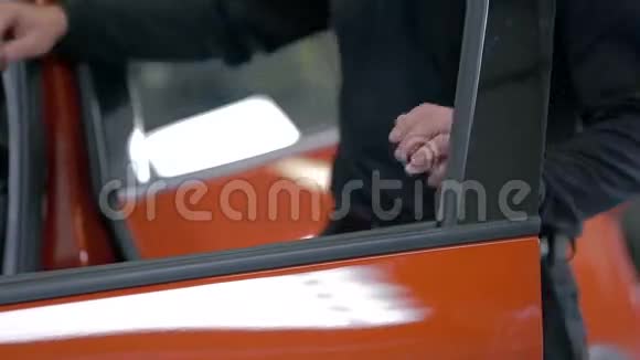 男人关上一辆红色汽车的门视频的预览图