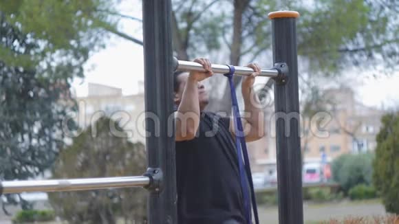 街头训练交叉健身男子做拉力带抗力带在户外健身房在公园视频的预览图