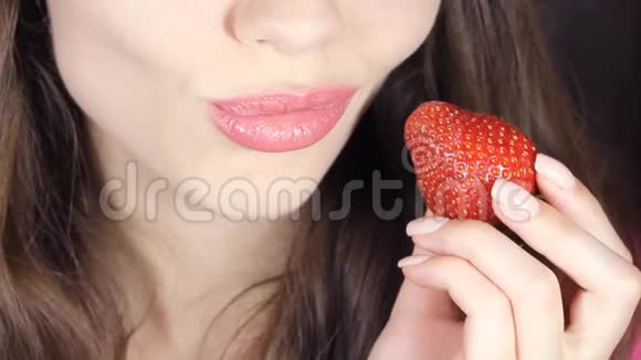 慢悠悠地吃草莓的女人性感的红唇红指甲和唇膏视频的预览图