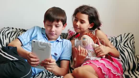 使用数码平板电脑进行游戏的幼儿小男孩和女孩在卧室里坐在床上玩平板电脑青少年视频的预览图