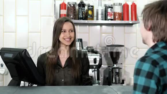 漂亮的女咖啡师从一位顾客那里点餐顾客在咖啡店里放了一个平板电脑她微笑着视频的预览图