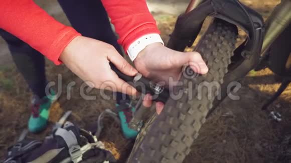 年轻的白种人女运动员骑自行车的人用手工具工具一个自行车泵把空气充气到轮胎轮山视频的预览图