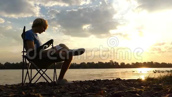 创意人阅读在斯隆莫的日落河畔锻炼视频的预览图