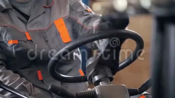 关闭方向盘和杠杆一个人驾驶叉车穿过工厂的仓库穿制服的司机视频的预览图