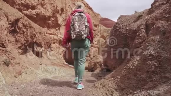 一个带背包的旅行者沿着不寻常的地形行走后景红色的山脉和红色的地球就像火星一样视频的预览图