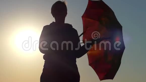 日落时分女人旋转一把棕色的伞视频的预览图