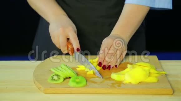女性用手在木板上切割猕猴桃和芒果视频的预览图